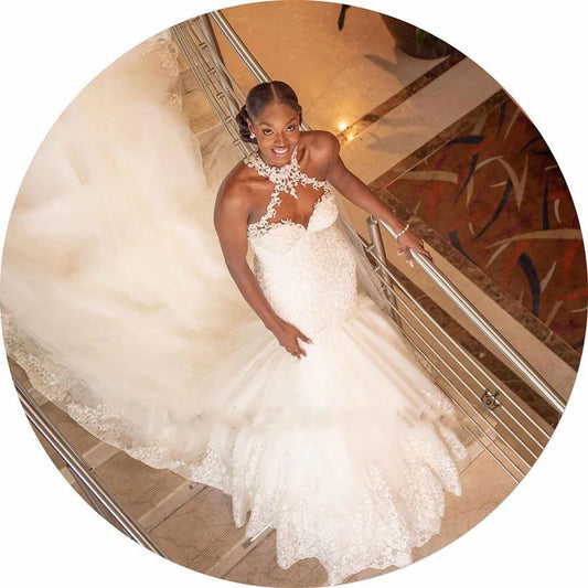 Elegant white lace wedding dress with halter neckline, worn on staircase for bridal photoshoot